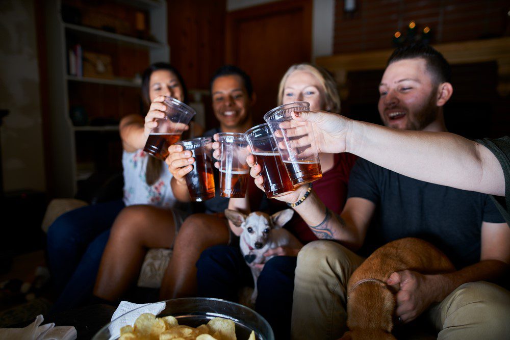 friends toasting with with alcohol and salty snacks that are foods that are harmful to dogs