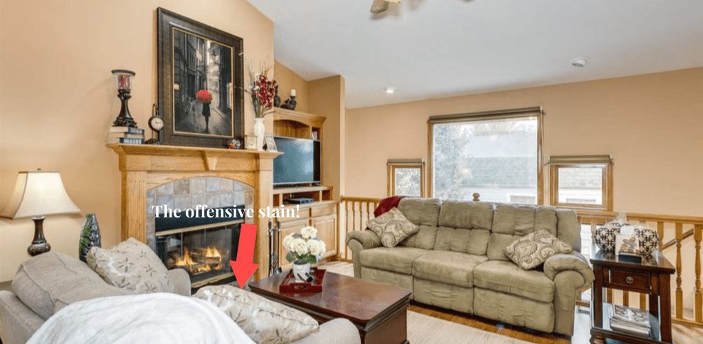 a living room with fireplace, love seat, green couch, coffee table, and a light colored area rug